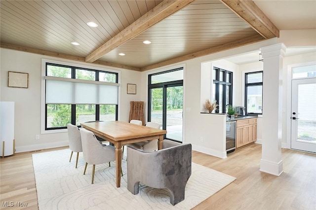 dining room featuring beam ceiling, light hardwood / wood-style floors, and a wealth of natural light