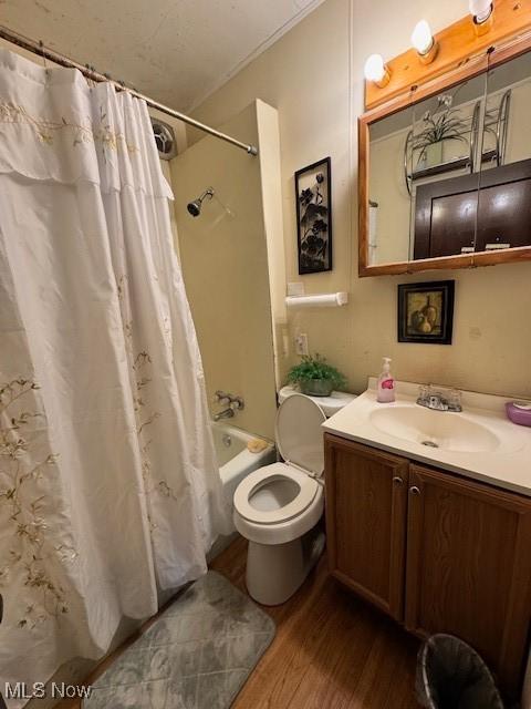 full bathroom with toilet, hardwood / wood-style flooring, shower / bath combo with shower curtain, vanity, and ornamental molding