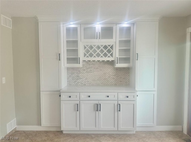 kitchen with white cabinets, decorative backsplash, and light tile patterned floors