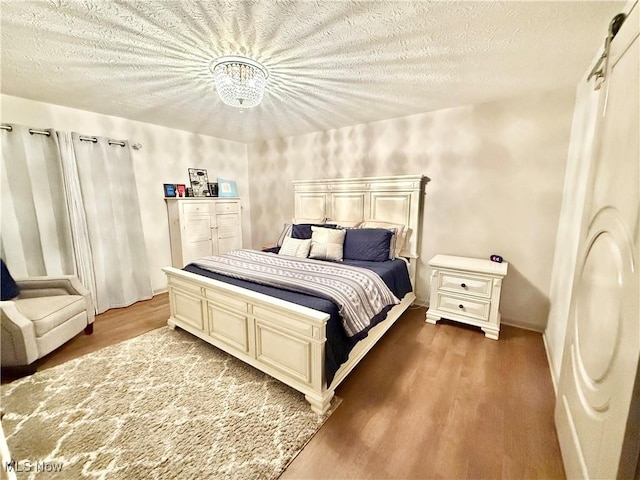 bedroom with hardwood / wood-style floors, a textured ceiling, and an inviting chandelier