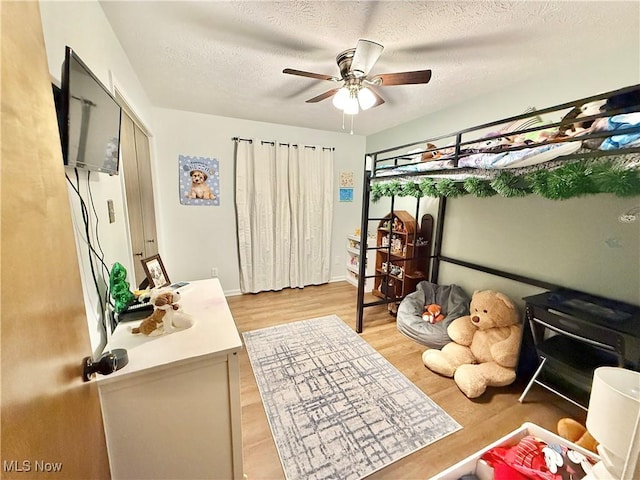 bedroom featuring ceiling fan, a textured ceiling, and light wood-type flooring