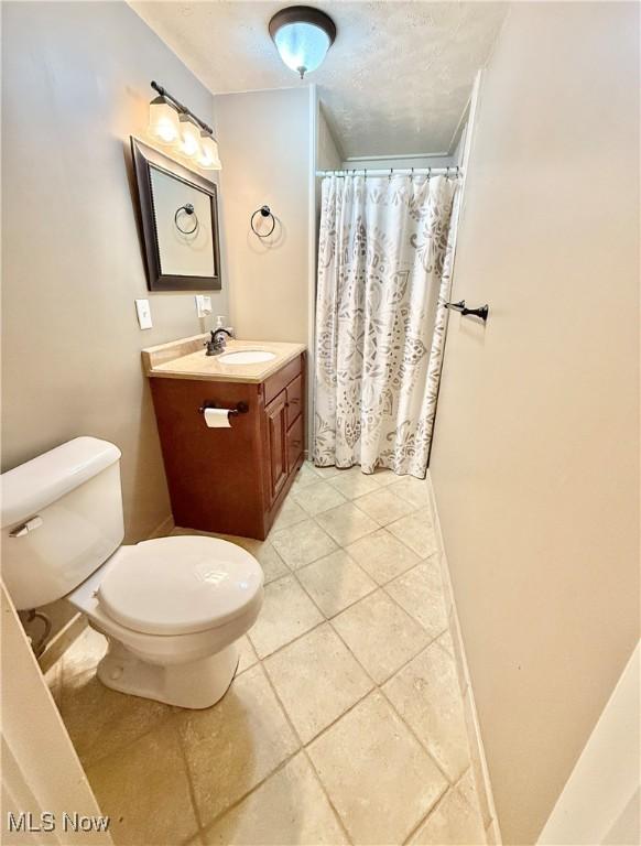 bathroom with tile patterned floors, a shower with curtain, vanity, and toilet