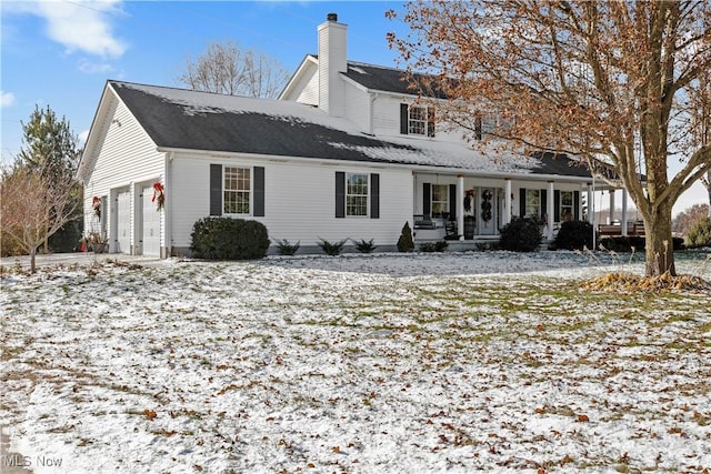 snow covered house featuring covered porch and a garage