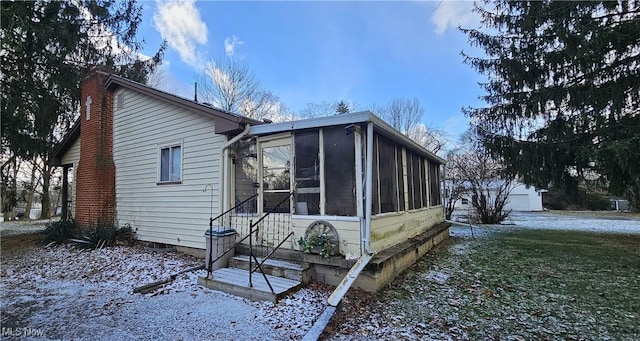 snow covered property featuring a sunroom and a yard