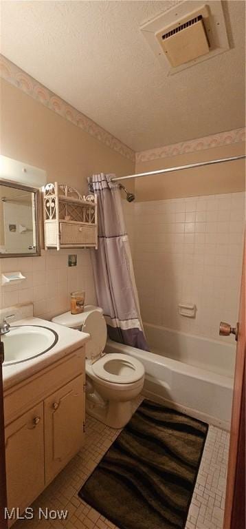 full bathroom with vanity, tile patterned flooring, toilet, shower / bath combo with shower curtain, and tile walls