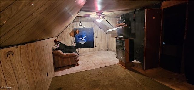 bonus room featuring ceiling fan, lofted ceiling, carpet floors, and wooden walls