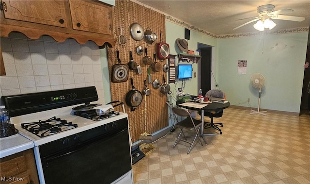 kitchen featuring white gas stove, ceiling fan, and backsplash