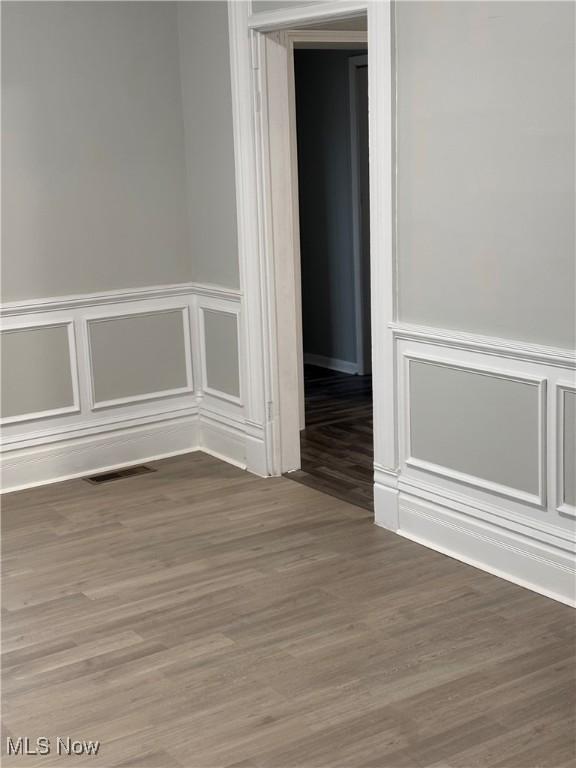 934 Main St, Wellsville, OH 43968 - unfurnished room featuring wood finished floors, a decorative wall, and a wainscoted wall