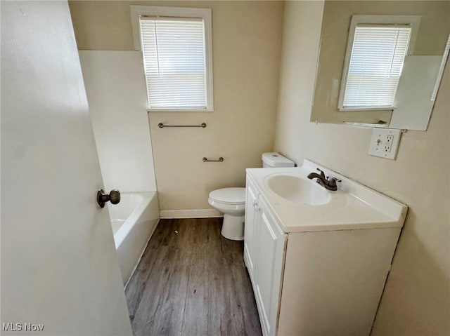 bathroom featuring hardwood / wood-style floors, vanity, a bath, and toilet