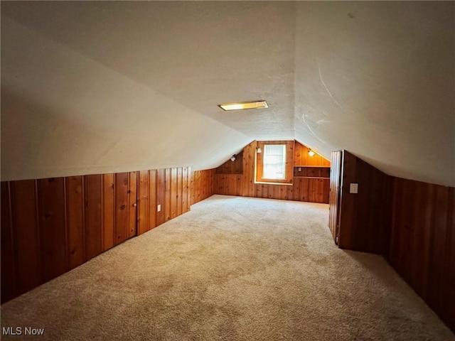 bonus room featuring carpet, wood walls, and lofted ceiling