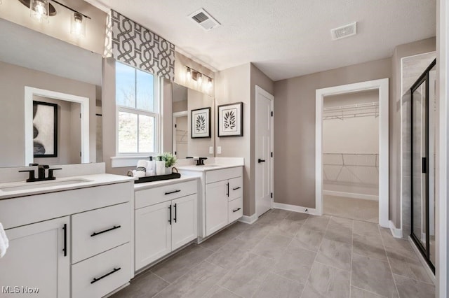 bathroom featuring tile patterned floors, vanity, a textured ceiling, and walk in shower