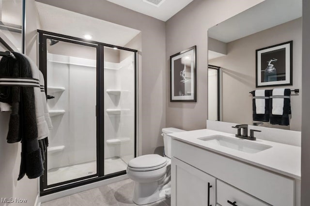 bathroom with tile patterned flooring, vanity, an enclosed shower, and toilet