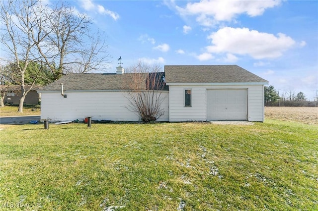 exterior space with a lawn, a garage, and an outdoor structure