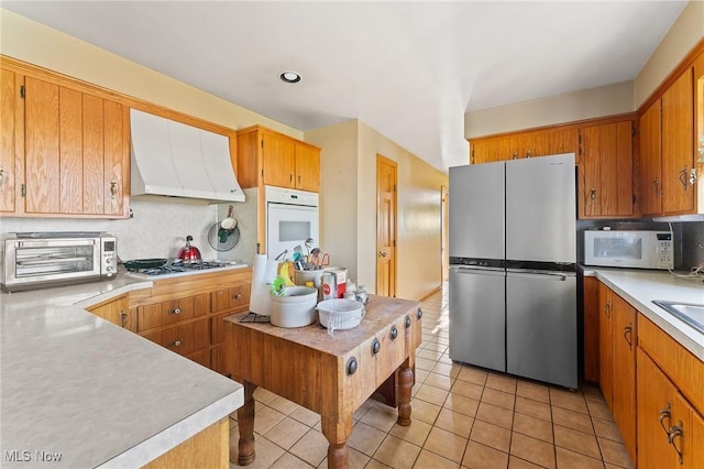 kitchen with decorative backsplash, appliances with stainless steel finishes, ventilation hood, and light tile patterned floors