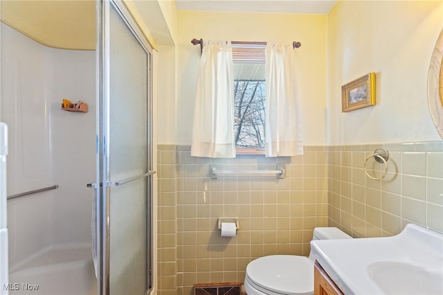 bathroom featuring walk in shower, vanity, tile walls, and toilet