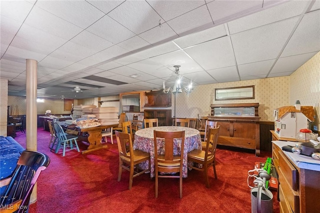 carpeted dining space with ceiling fan and a drop ceiling