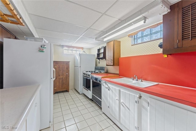 kitchen featuring a drop ceiling, white appliances, exhaust hood, sink, and light tile patterned floors