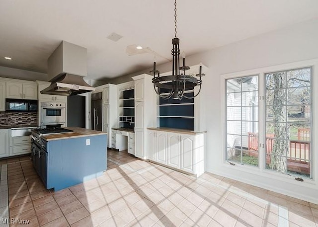 kitchen with white cabinetry, white double oven, tasteful backsplash, ventilation hood, and a notable chandelier