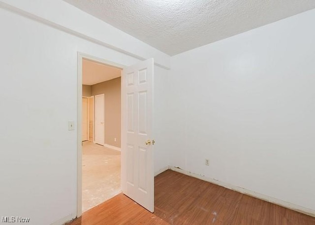 spare room with light hardwood / wood-style floors and a textured ceiling