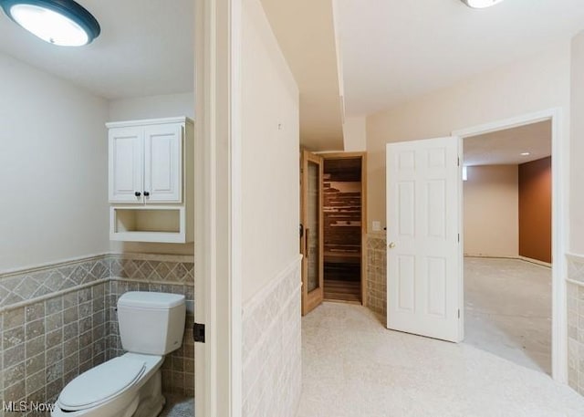 bathroom featuring toilet and tile walls