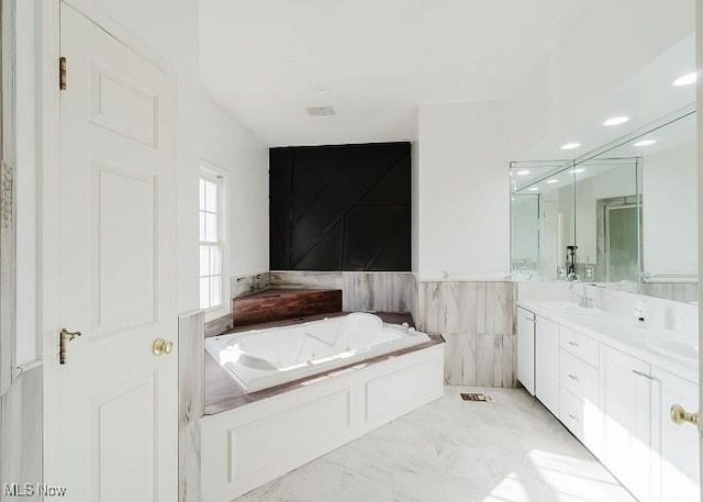 bathroom featuring vanity, tile walls, and a washtub