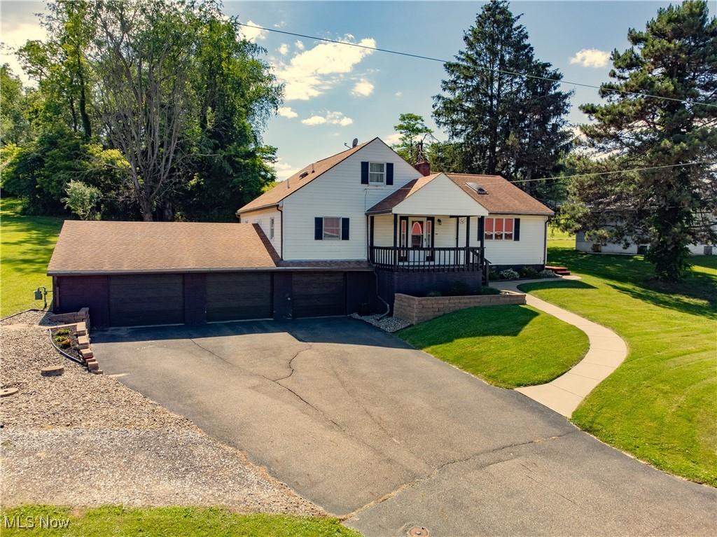 view of front of property featuring a front lawn, covered porch, and a garage