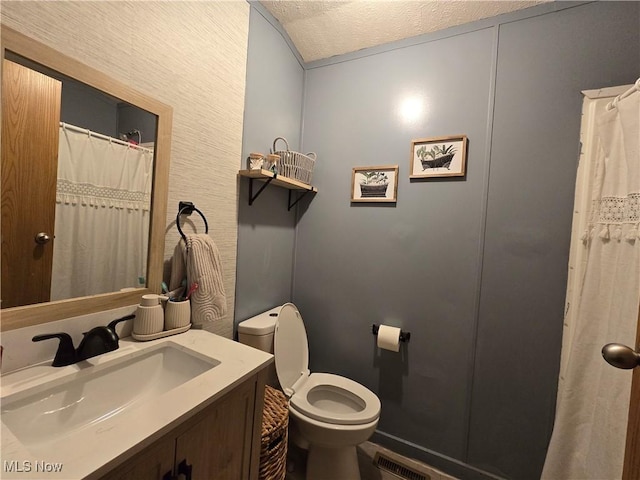 bathroom with vanity, toilet, and a textured ceiling