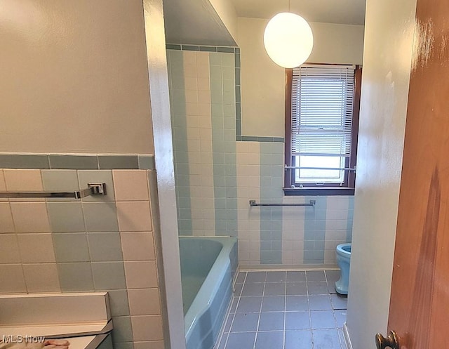 bathroom featuring a tub to relax in, tile patterned flooring, tile walls, and toilet