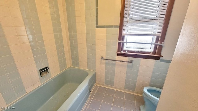 bathroom featuring tile patterned floors, a tub, tile walls, and toilet