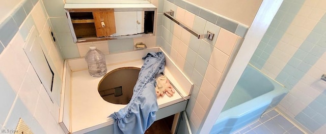 bathroom with a tub and tile walls