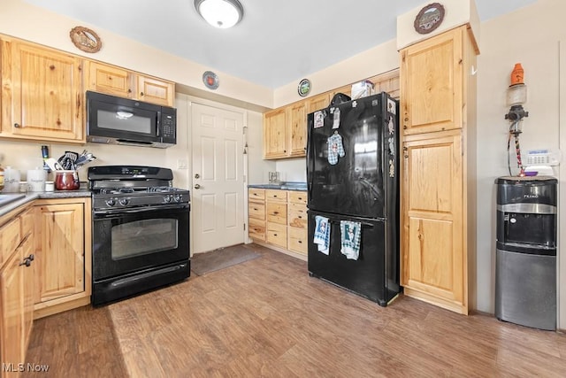 kitchen with light brown cabinetry, light hardwood / wood-style flooring, water heater, and black appliances