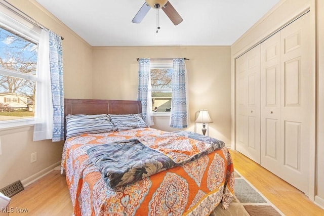 bedroom featuring light wood-type flooring, a closet, ceiling fan, and crown molding