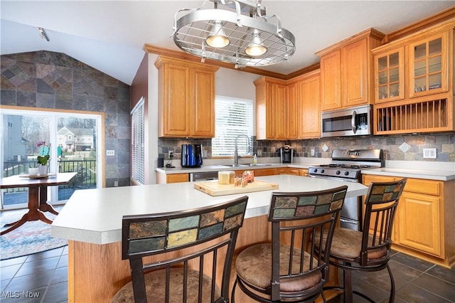 kitchen with appliances with stainless steel finishes, backsplash, sink, a center island, and lofted ceiling