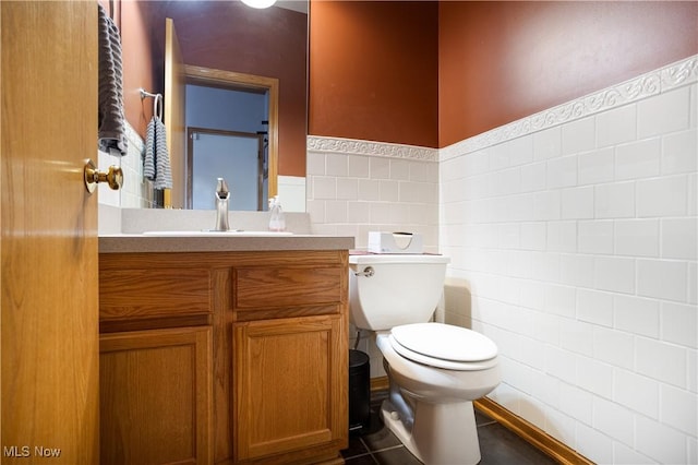 bathroom with tile patterned flooring, vanity, toilet, and tile walls