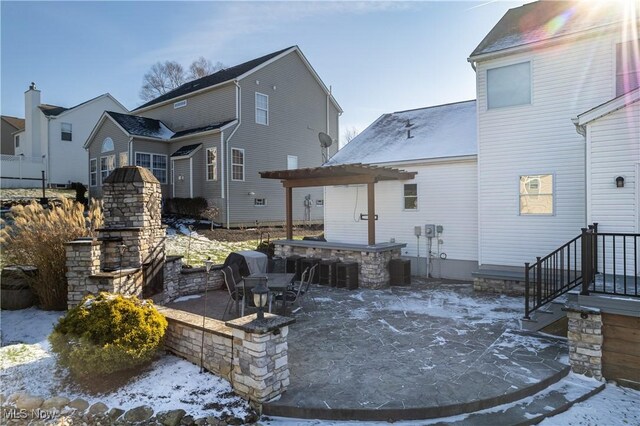 snow covered back of property featuring an outdoor stone fireplace, a patio, an outdoor bar, and central AC