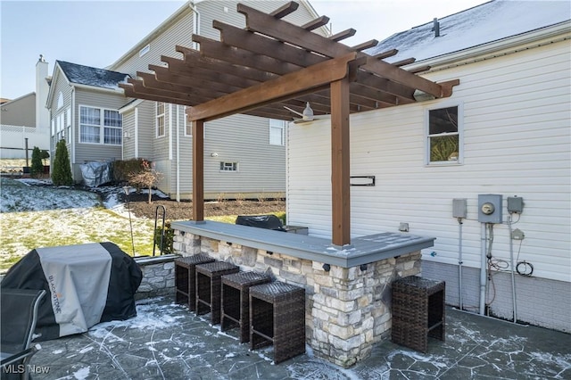 view of patio with area for grilling, a pergola, and exterior bar