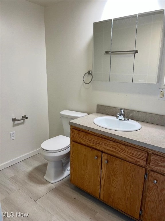 bathroom with wood-type flooring, vanity, and toilet