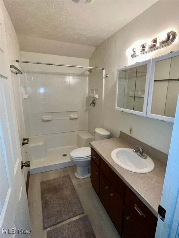 bathroom featuring tiled shower, toilet, a textured ceiling, and vanity