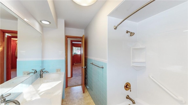 bathroom featuring sink, a baseboard radiator, tile walls, and washtub / shower combination