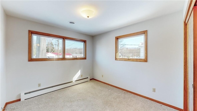 carpeted empty room featuring a wealth of natural light and a baseboard heating unit