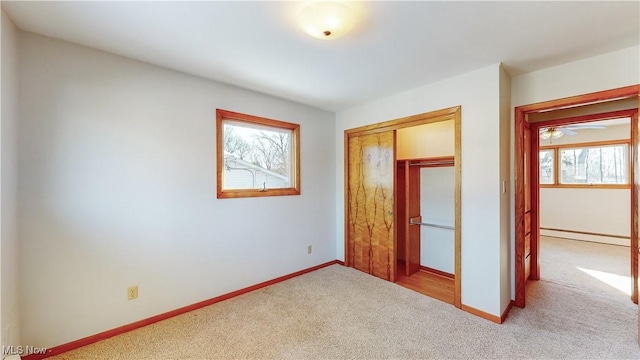 unfurnished bedroom with light colored carpet, a baseboard radiator, and a closet