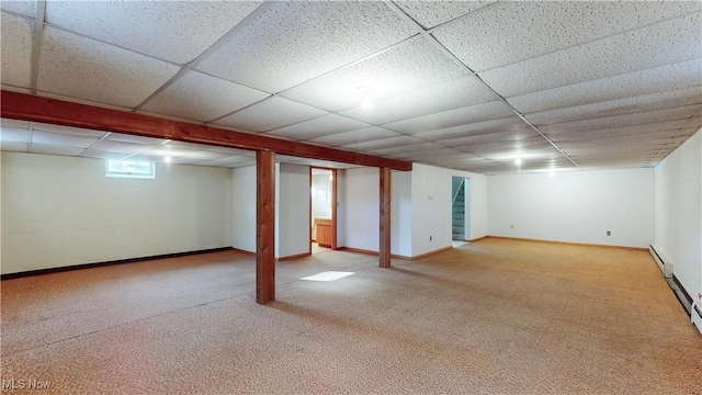 basement featuring light carpet, a paneled ceiling, and a baseboard radiator