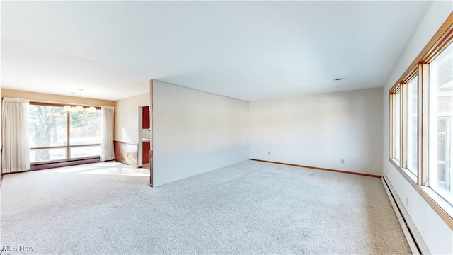 carpeted spare room featuring an inviting chandelier and a baseboard heating unit