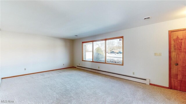 carpeted spare room with a baseboard heating unit