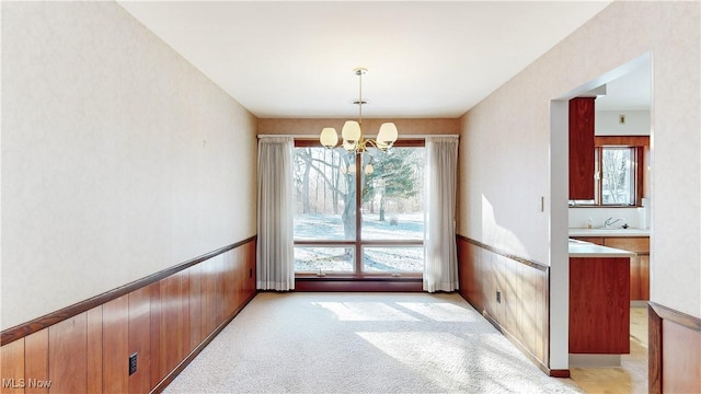 unfurnished dining area with light carpet, a notable chandelier, and sink