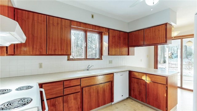 kitchen with sink, kitchen peninsula, extractor fan, white appliances, and decorative backsplash