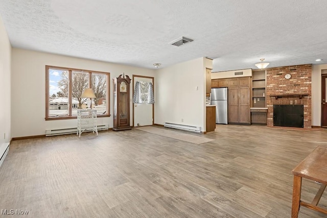 unfurnished living room featuring a fireplace, light hardwood / wood-style flooring, a textured ceiling, and a baseboard heating unit