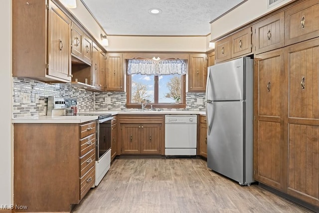 kitchen with a textured ceiling, white dishwasher, electric stove, light hardwood / wood-style flooring, and stainless steel refrigerator