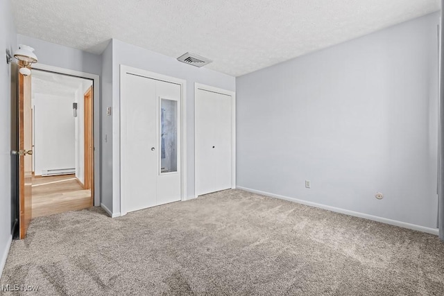 unfurnished bedroom with carpet, a textured ceiling, and a baseboard radiator