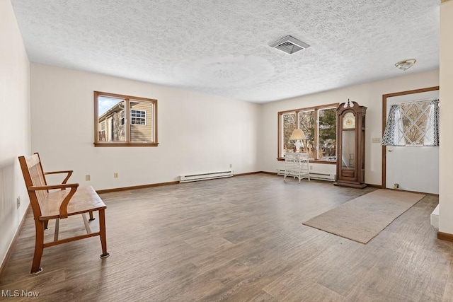 unfurnished room featuring baseboard heating, a textured ceiling, and hardwood / wood-style flooring